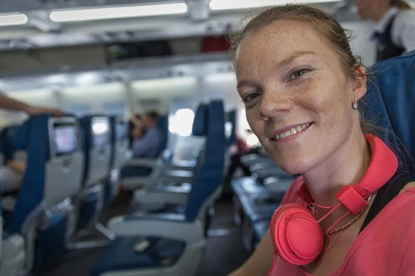 Mladá dáma na palubě letadla poslouchat hudbu — Stock fotografie