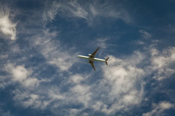 Ett plan som flyger blå himmel med moln i bakgrunden — Stockfoto