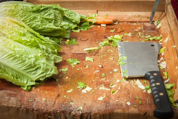 Cuchillas de verduras en una tabla de madera para satisfacer la lechuga — Foto de Stock