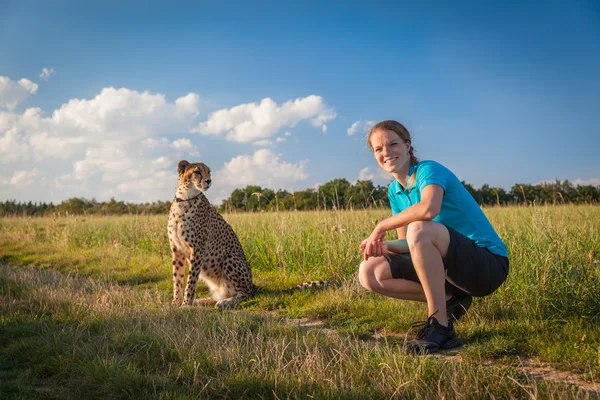 Young woman on a green meadow in summer walking cheetah — Stock Photo, Image