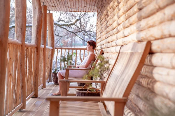 Mujer se relaja después de la sauna en una cabaña de madera en invierno — Foto de Stock