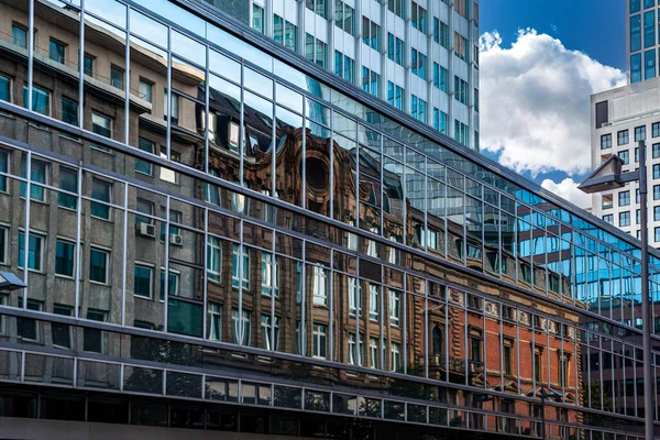 Reflektioner av stadsbyggnader i fönstrens glasytor — Stockfoto