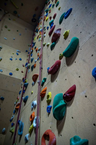 현대 체육관에서 여러 가지 색깔의 손잡이로 벽을 오르는 모습 — 스톡 사진