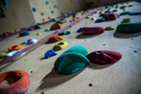 Ścianka wspinaczkowa z różnymi kolorowymi uchwytami w nowoczesnej siłowni — Zdjęcie stockowe