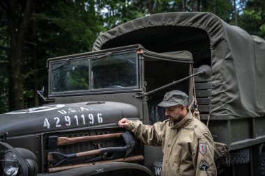 Askeri üniformalı bir adam askeri bir arabada.