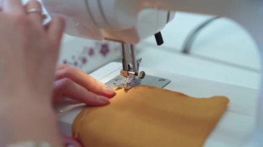 Elbise dikmek için dikiş makinesine kumaş dikiyorum.