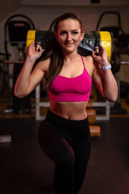 Spor salonunda spor çantasıyla egzersiz yapan genç bir kadın.