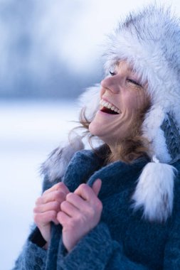 Yüzünde bir gülümsemeyle kışlık giysiler içinde güzel bir kadın.