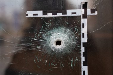 Camcıdaki kurşun delikleri polis bandıyla işaretlenmiş.