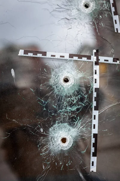 Einschusslöcher in einem gläsernen Schaufenster, markiert mit einem Polizeiband — Stockfoto