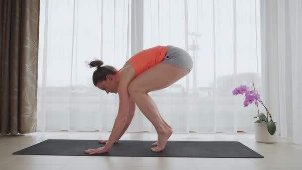 Attraktiv fitness kvinna utövar yoga hemma. Kråkans position — Stockvideo
