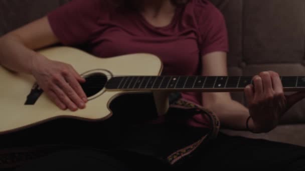 Уроки домашньої гітари онлайн. жінка грає на гітарі вдома на дивані . — стокове відео