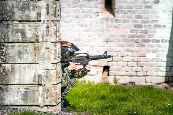 Donna in uniforme con una pistola in addestramento paintball militare — Foto Stock