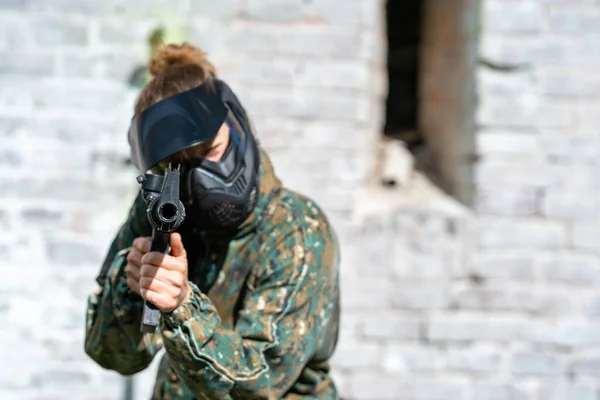 Giovane donna in azione mentre gioca a paintball — Foto Stock