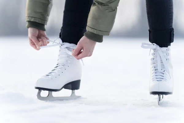 A téli korcsolyák csipkéinek megkötése egy befagyott tavon, korcsolyázás — Stock Fotó