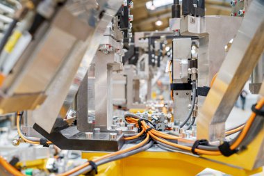 Modern bir fabrika üretim hattında otomotiv parçaları birleştiren endüstriyel robotik silahlar, hassas imalat, otomasyon teknolojisi ve verimli endüstriyel mühendislik.