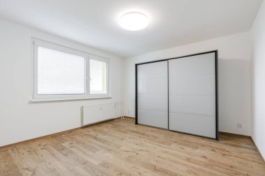 Boş, mobilyasız, beyaz duvarlı, ahşap zemin kaplamalı, penceresi kör, sürgülü, gardırop ve tavan aydınlatmalı, iç dekorasyona hazır.