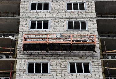 İnşaat beşik işçiler olmadan bir yeni inşa edilen yüksek katlı bina askıya.