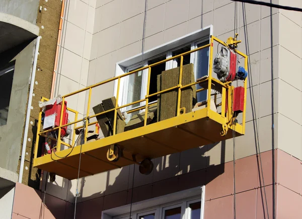 Construction suspended yellow cradle without workers on a newly built high-rise building — Stock Photo, Image