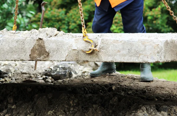 İşçi, tamir sırasında vinç kancalarına beton levhanın içindeki halkalara dokunur.