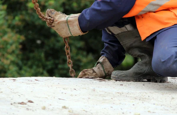 İşçi, tamir sırasında vinç kancalarına beton levhanın içindeki halkalara dokunur.