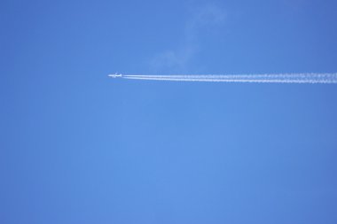 Mavi gökyüzünde uçan beyaz çizgili bir jet uçağı