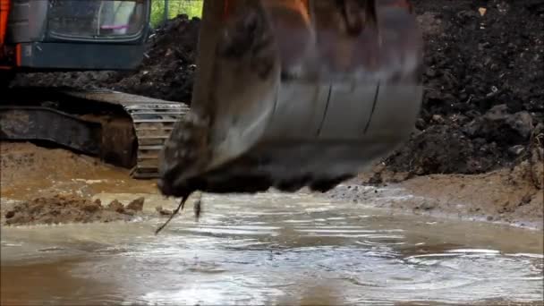 道路の修理のための建設現場で浸水の溝に水を引くための掘削機のバケツ. — ストック動画