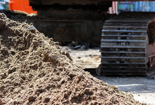 キャタピラー掘削機と道路を修復するための建物建設現場の砂の山 — ストック写真