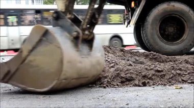 Yol bölümünde onarım var. İşçiler traktörle küçük bir alanı kovayla onarıyor. Asfalt kaldırılmış, çakıllar geri doldurulmuş ve doldurulmuş. raporlama.