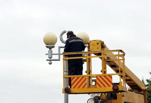 Pekerja listrik memperbaiki kabel-kabel di tiang dengan bantuan lift mobil . — Stok Foto