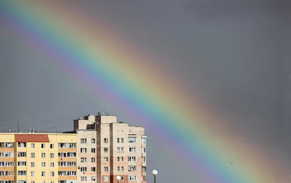 町家の上の灰色の空の嵐の後に明るい多色の広いカラフルな虹 — ストック写真