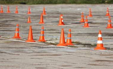Sürücülerin sınavı doğru kamyonlarla geçtiği yerde bir sürü plastik trafik konisi duruyor.