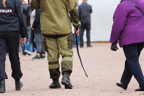 Bewaker van een particuliere beveiligingsdienst patrouilleert op het plein met mensen die een zweep vasthouden tijdens een nationale feestdag. — Stockfoto