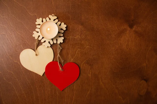 茶色の背景にバレンタインデーのための2つの木製の心とキャンドル — ストック写真