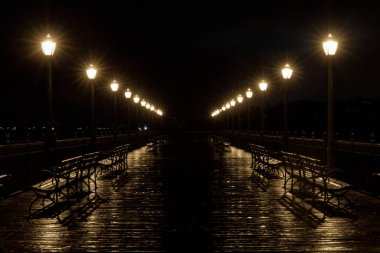 İskele 7 'de lamba direkleri ve yağmur yansımaları parlıyor. Embarcadero, San Francisco, California, ABD.