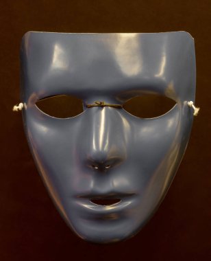Boş Yüzlü Gümüş-Gri Maske Kırmızı-Kahverengi Arkaplan Karşısında İzole Edildi.