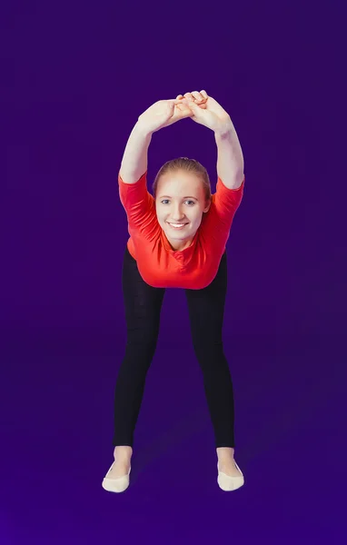 Woman in red doing exercises while standing on a blue background in the fitness room — Stock fotografie