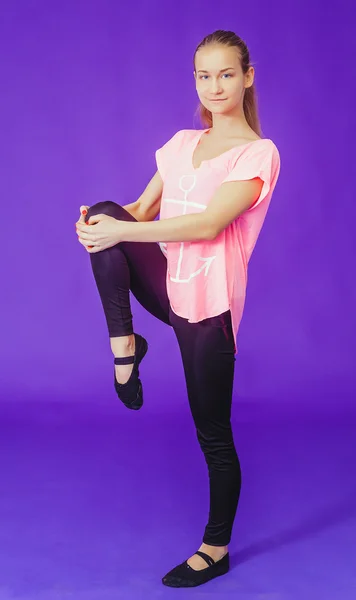 Woman in red doing exercises while standing on a blue background in the fitness room — Stock fotografie