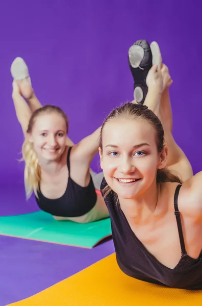 Γυμναστήριο, αθλητισμό, εκπαίδευση και τον τρόπο ζωής έννοια - χαμογελώντας δύο σπορ γυναίκες κάνει ασκήσεις σε χαλί στο γυμναστήριο — Φωτογραφία Αρχείου
