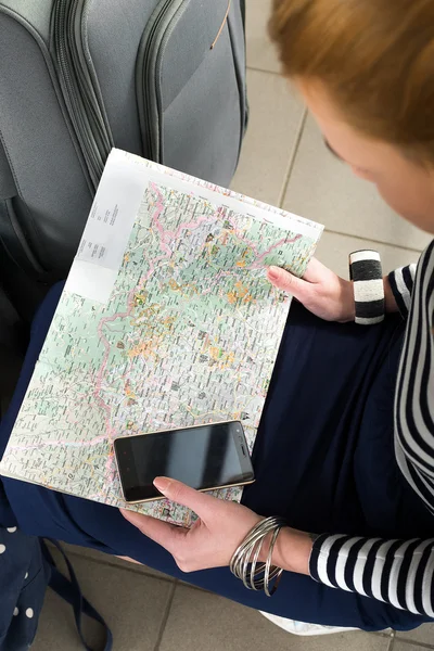 Νεαρή γυναίκα κάθεται με ένα δισκίο και κοιτάζει το χάρτη. Κοντινό πλάνο. συγκεντρώθηκαν σε ένα ταξίδι. — Φωτογραφία Αρχείου