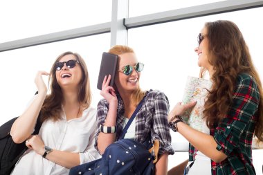 Üç genç kadın ayakta Havaalanı ve gülmek güneş gözlüğü. Arkadaş grubu bir gezi