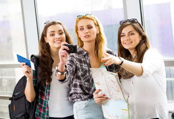 Tři dívky stojí na letišti a při pohledu na tabletu. Výlet s friends.girls dělají selfie — Stock fotografie