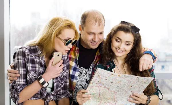 young man and two women looking at a map. Europeans. Americans. Gathered in a guided tour. Close-up