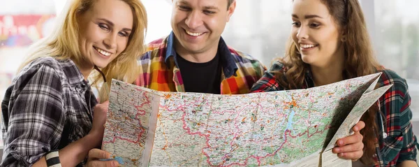 Un giovanotto e due donne che guardano una mappa. Europei. Americani. Riuniti in una visita guidata. Primo piano — Foto Stock