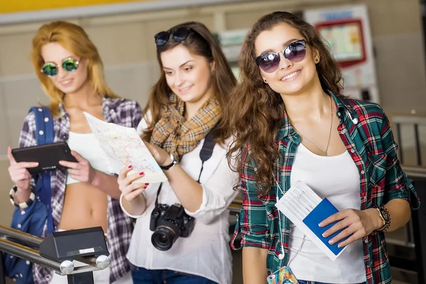Üç genç kadın istasyonu veya havaalanında tutan bir kamera, kart, bir pasaport, bir tablet. Avrupalılar. 