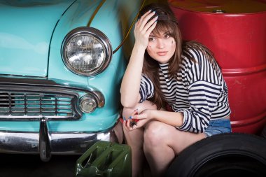 bir kap içinde kadın yorgun retro car yakınındaki garajda araçları ile oturuyor. Pense tutan kız ve başından ele aldı