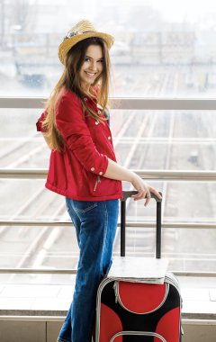 bir kırmızı palto ve şapka ayakta Terminal veya bavulla istasyonunda genç çekici kadın. 