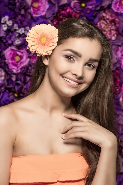 Портрет красивої усміхненої молодої жінки з квітковою герберою. на фоні настінна квітка — стокове фото
