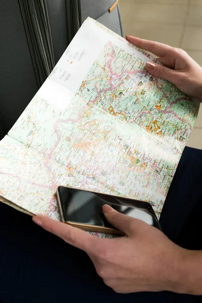 Γεωγραφικός χάρτης της Λέσβου και τηλέφωνο. Άποψη από ψηλά. Τα χέρια του κοριτσιού κρατώντας μια κάρτα και ένα κινητό τηλέφωνο — Φωτογραφία Αρχείου