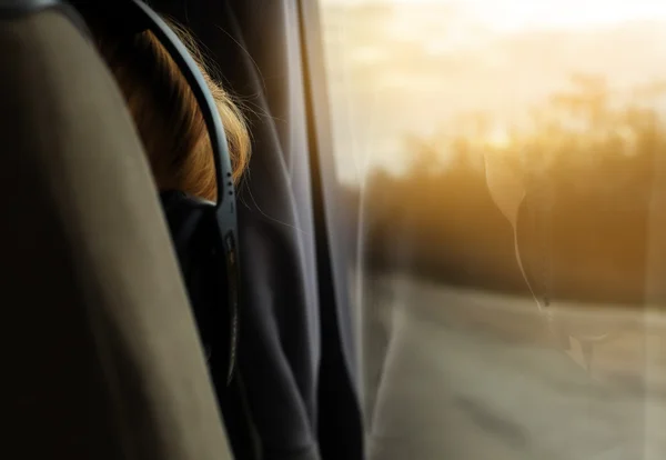 A reflection of a girl with headphones in the bus window. back view. close-up. On the Sunset — Stock Photo, Image